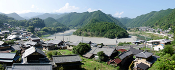 青空の下、山々に囲まれた沢山の家が、円型に建ち並ぶ集落の写真