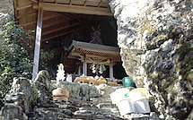 大きな岩に囲まれた場所に建てられたお堂の写真