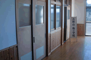 廊下の扉の前に、「吉野山 桜の学校」と書かれた看板が、設置されている写真