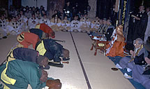 座りながら手を合わせて祈っている僧侶たちに向かって土下座をしている鬼たちの写真