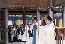 神殿内で神楽鈴を手にし祈りを捧げる巫女たちの写真