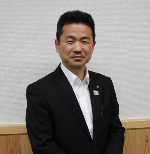 吉野町長である中井あきもとさんの写真。黒のスーツに白シャツ姿。カメラ目線。