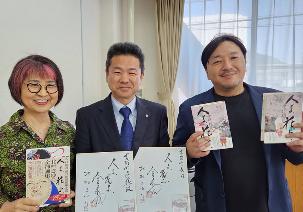楠木物語紀行 今村翔吾著「人よ、花よ」刊行記念イベント。刊行された著書と色紙を持って笑顔で写る3人。左から北村さゆり氏、中井町長、今村翔五氏。