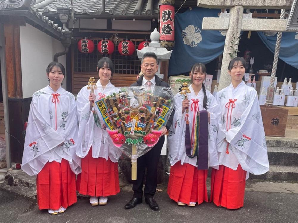 上市蛭子神社初市の様子。中井町長を真ん中にして両端に2名ずつ巫女が並び笑顔で写っている。