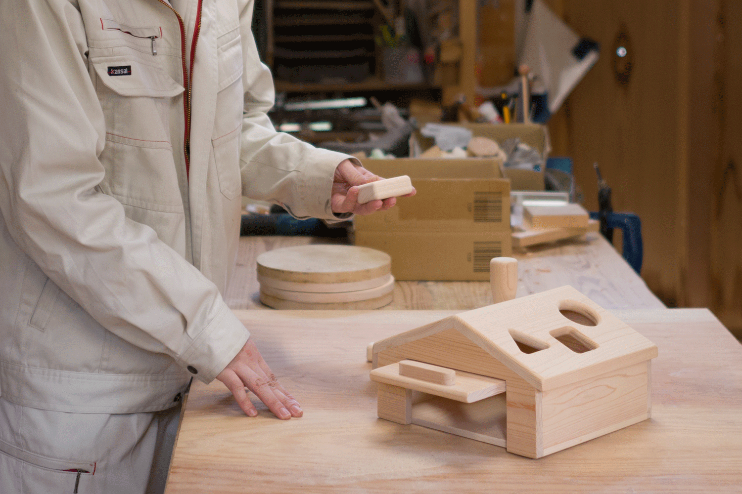 木工素材で作る木のおもちゃの作成風景。背景には木工製作に使う工具等が並ぶ。