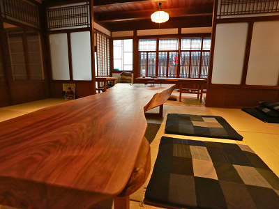 古民家を活用したカフェの様子。畳の上に天然木を使った低いテーブルと座布団が置いてある。