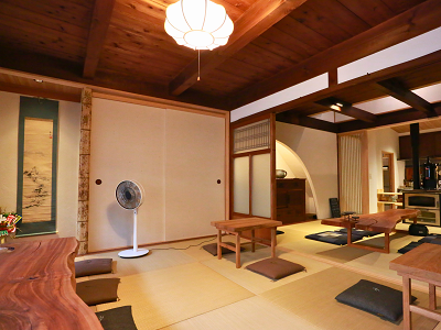 吉野町内にあるカフェ「コヤ」の室内。畳の上に天然木を活用した低めのテーブルと座布団が複数並べられている。