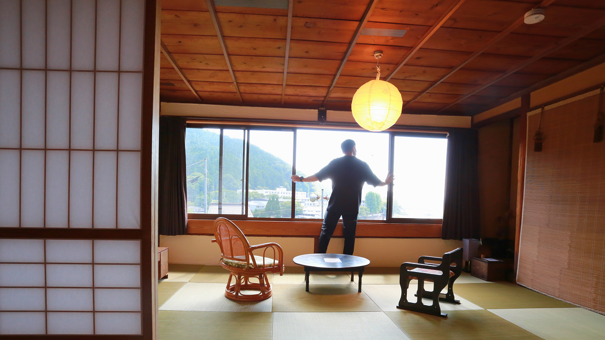 吉野町にあるゲストハウス「のび」の室内。窓を開ける男性の様子。