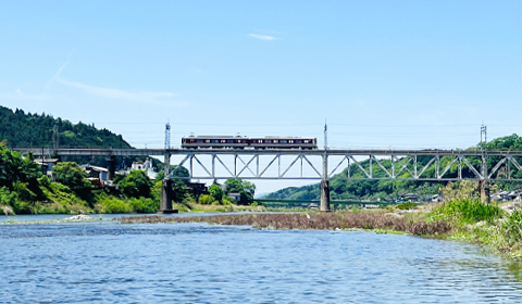 吉野川から見える橋梁と電車の風景。電車は二両編成の近鉄電車。