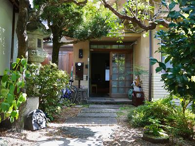 光がさしている古民家の玄関。庭には緑が広がっている。