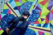 カラフルな背景をバックにした永野 貴志さんの写真