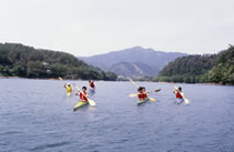 山間の湖でカヤックを楽しむ人たちの写真