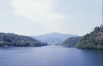 青空のもと湖の中央から山を望む写真
