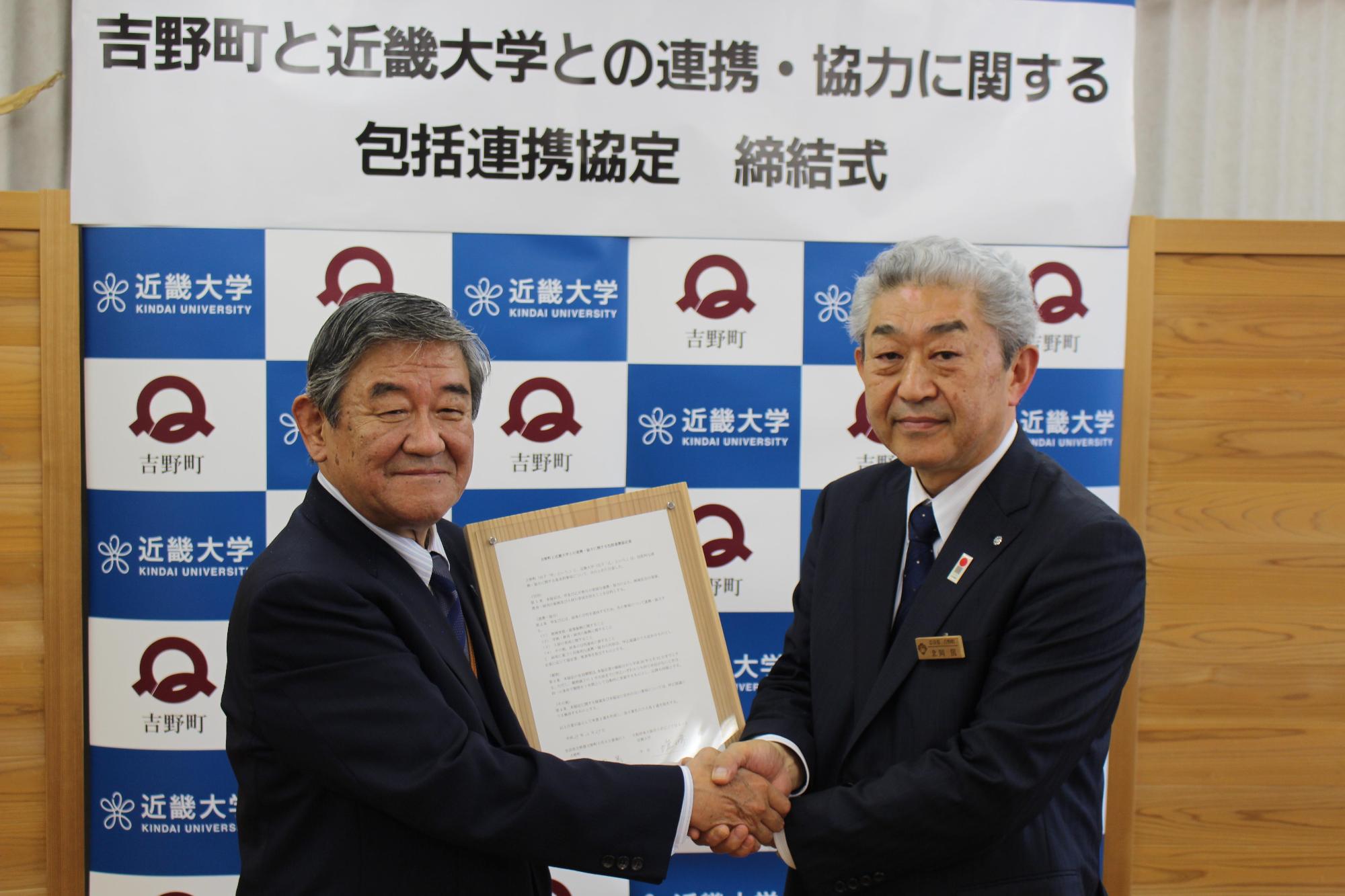 吉野町と近畿大学との連携・協力に関する包括連携協定締結式にて近畿大学増田大三副学長と北岡町長が固く握手をしている写真