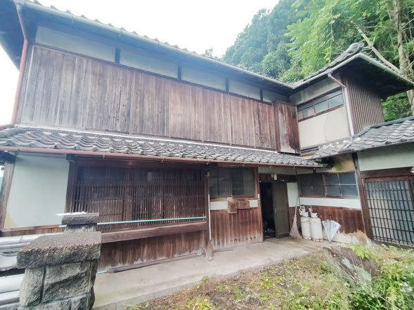 庭を囲うように建つエル字型木造2階建ての建物の写真