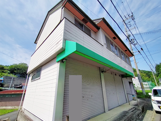 外壁は白く元店舗で1階はシャッターが閉まっている。
