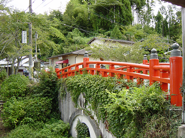 朱塗りの欄干と緑色の草木のコントラストが美しい橋の写真