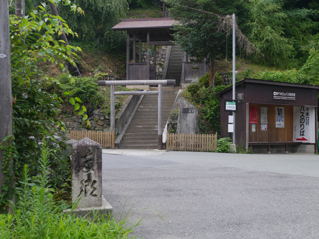 茶色の鳥居から続く階段と門、屋根付きのバス乗合所など風情ある町並みの写真